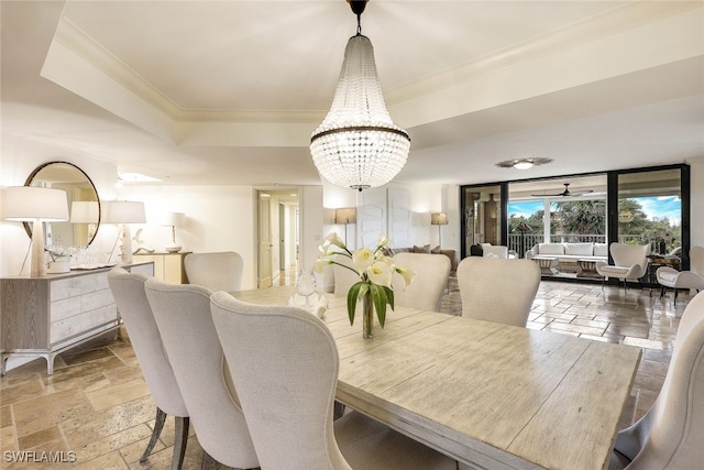 dining area with ceiling fan with notable chandelier, a raised ceiling, and crown molding