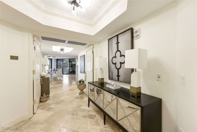 hallway with a tray ceiling and crown molding