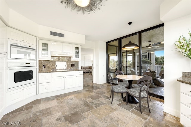 kitchen featuring white cabinets, pendant lighting, dark stone counters, and tasteful backsplash