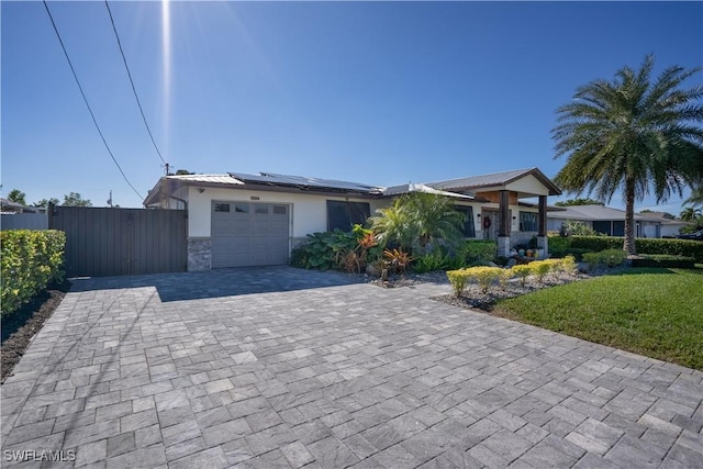 view of front of property with a front lawn, a garage, and solar panels