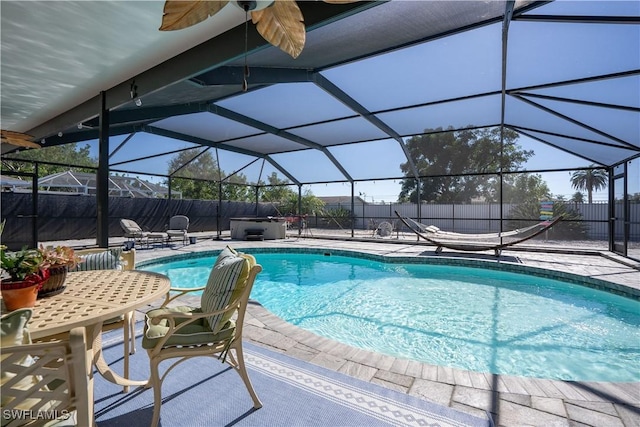 view of pool featuring a patio, glass enclosure, and ceiling fan