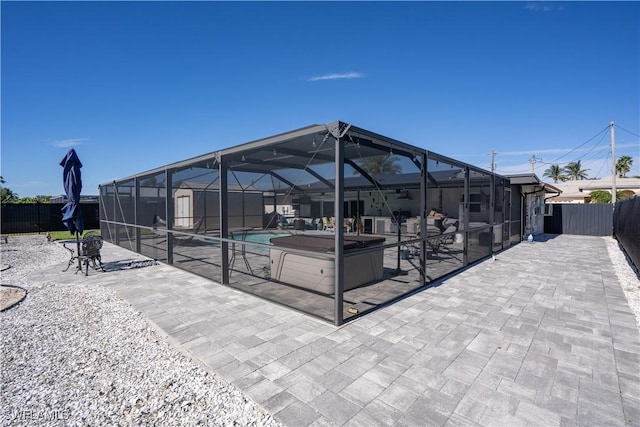 view of patio featuring glass enclosure and a pool with hot tub