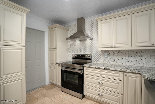 kitchen featuring tasteful backsplash, crown molding, wall chimney range hood, cream cabinets, and stainless steel electric range