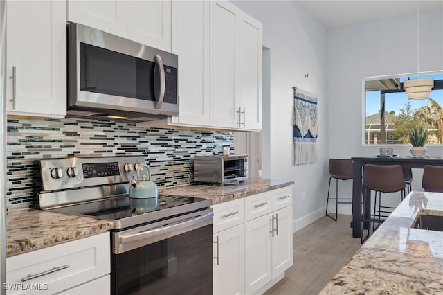 kitchen with white cabinets, appliances with stainless steel finishes, and light wood-type flooring