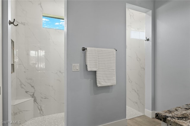 bathroom with tiled shower and wood-type flooring