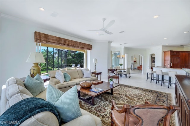 living room with light tile patterned floors, ceiling fan with notable chandelier, and ornamental molding