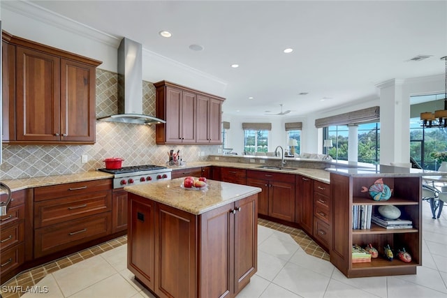 kitchen with kitchen peninsula, stainless steel gas cooktop, sink, wall chimney range hood, and a center island