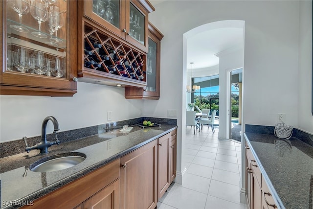 kitchen with light tile patterned floors, sink, and dark stone counters