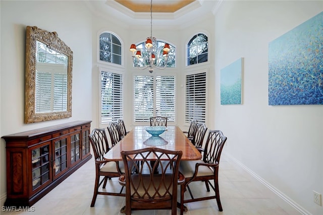 dining space featuring a tray ceiling, ornamental molding, light tile patterned floors, and a chandelier