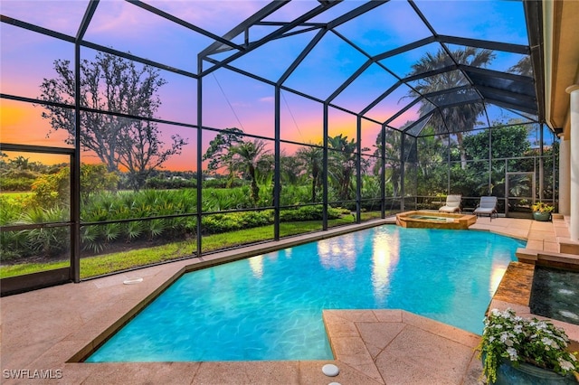 pool at dusk with an in ground hot tub, a patio, and a lanai