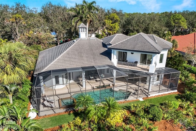 rear view of house with a lanai, a patio area, and a balcony