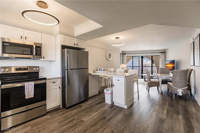 kitchen featuring white cabinets, dark hardwood / wood-style flooring, kitchen peninsula, and stainless steel appliances