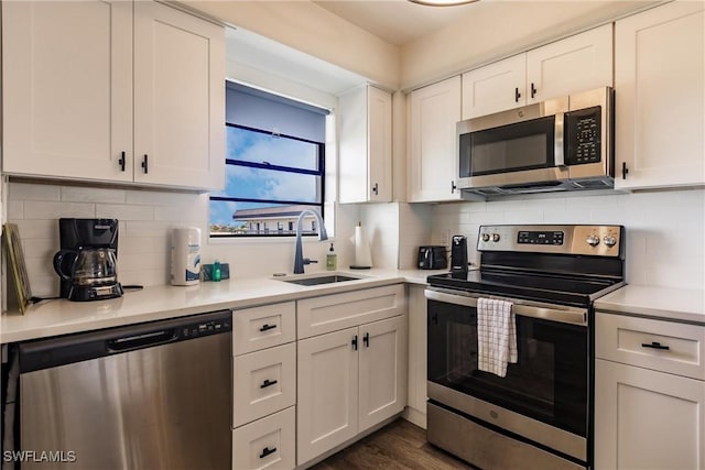 kitchen featuring sink, decorative backsplash, appliances with stainless steel finishes, dark hardwood / wood-style flooring, and white cabinetry