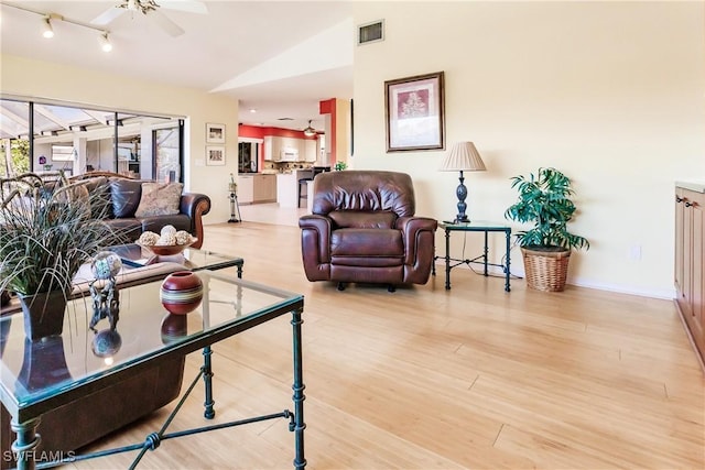 living room featuring ceiling fan, light wood-type flooring, and vaulted ceiling