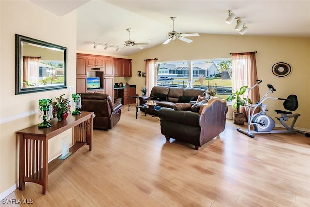 living room with ceiling fan, light hardwood / wood-style floors, and vaulted ceiling