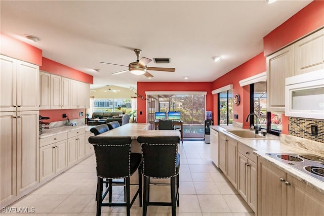 kitchen with a center island, a kitchen bar, light tile patterned floors, and sink