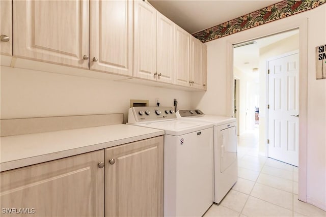 laundry area with washer and dryer, light tile patterned floors, and cabinets