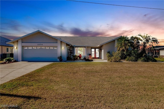 single story home featuring a lawn, a garage, and french doors