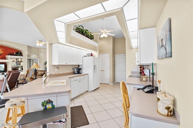 kitchen featuring kitchen peninsula, white appliances, ceiling fan, sink, and white cabinets