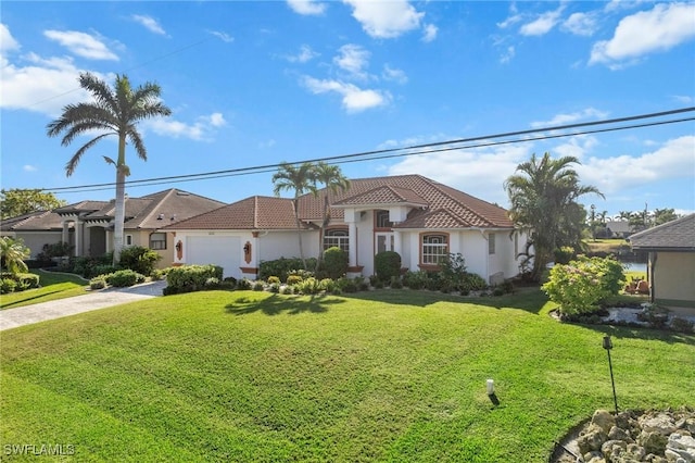 mediterranean / spanish home featuring a front yard and a garage