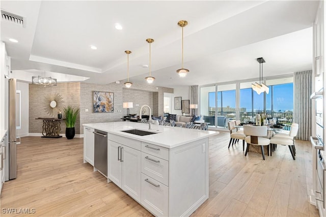 kitchen featuring sink, pendant lighting, a wall of windows, white cabinets, and light hardwood / wood-style floors