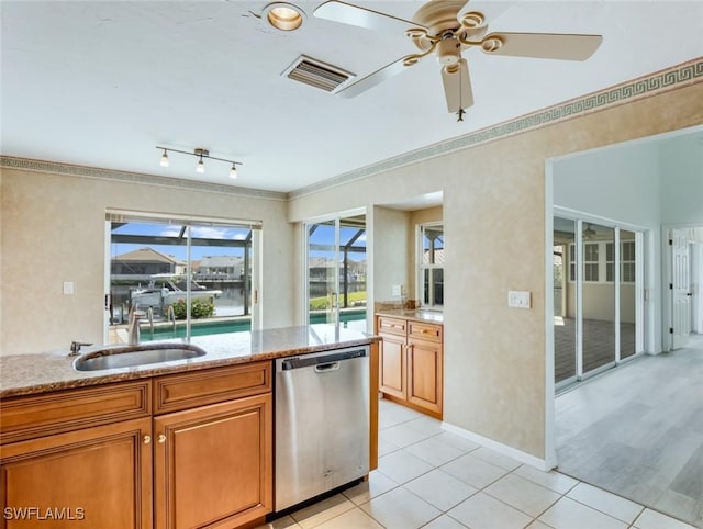 kitchen with dishwasher, sink, ceiling fan, light stone countertops, and light tile patterned flooring