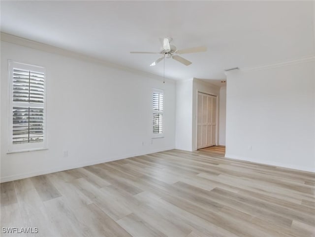 spare room with a wealth of natural light, crown molding, and light wood-type flooring