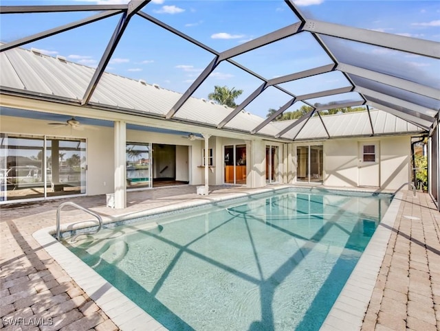 view of swimming pool with glass enclosure, ceiling fan, and a patio area