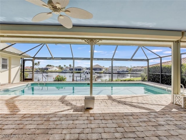 view of swimming pool with ceiling fan, a water view, and glass enclosure