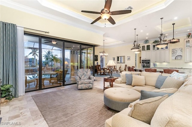 living room with a raised ceiling, ceiling fan with notable chandelier, and crown molding