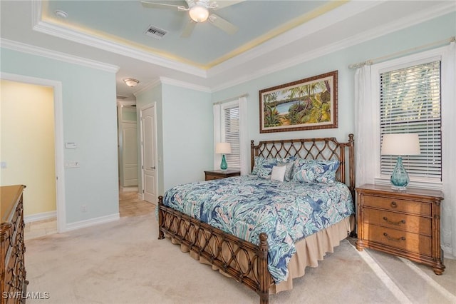 bedroom with ceiling fan, crown molding, a tray ceiling, and light carpet