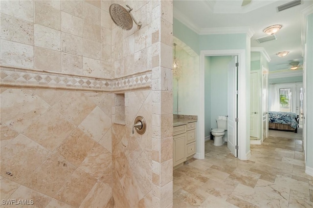 bathroom featuring toilet, crown molding, tiled shower, and vanity