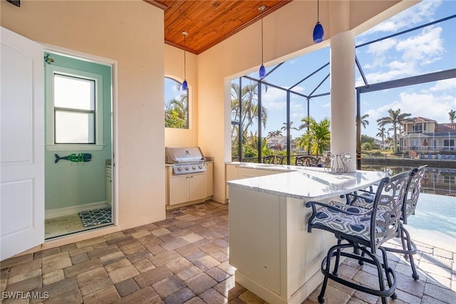 view of patio with glass enclosure, an outdoor bar, an outdoor kitchen, and area for grilling