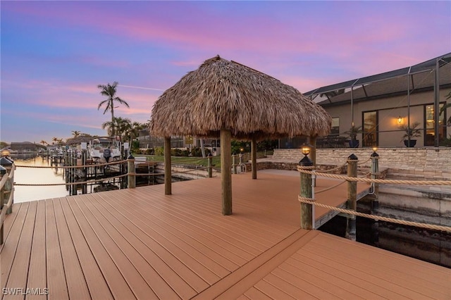 view of dock with a water view, a gazebo, and a lanai