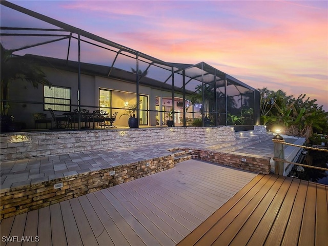 deck at dusk featuring a lanai and a patio