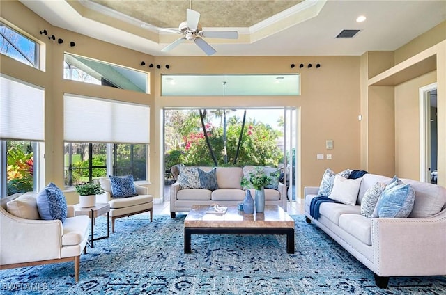 living room with a tray ceiling, plenty of natural light, and ceiling fan