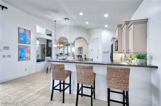 kitchen featuring kitchen peninsula, a breakfast bar, light tile patterned floors, and gray cabinetry