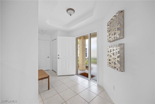 entryway featuring light tile patterned floors and a tray ceiling