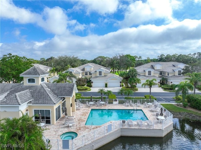 view of pool featuring a patio area, a water view, and a hot tub