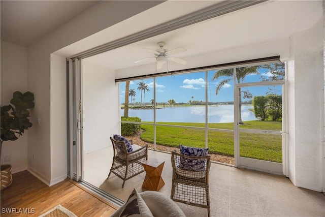 sunroom / solarium featuring a water view and ceiling fan