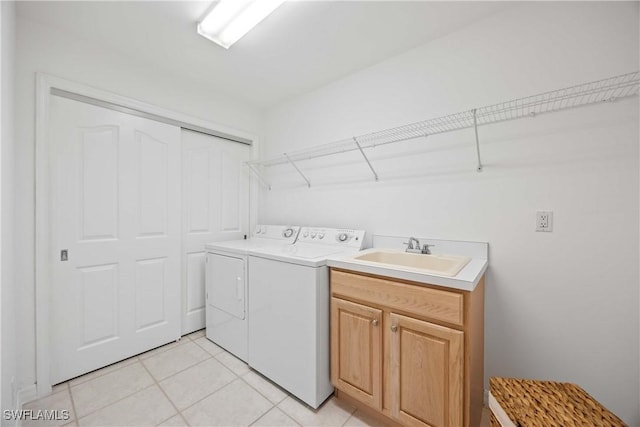 clothes washing area with washer and dryer, light tile patterned flooring, cabinets, and sink