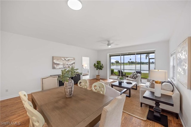 dining space with a water view, light hardwood / wood-style flooring, and ceiling fan