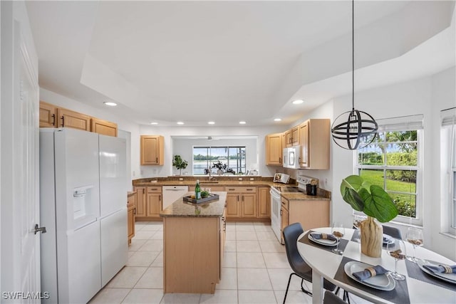 kitchen with white appliances, light brown cabinets, stone countertops, a center island, and hanging light fixtures