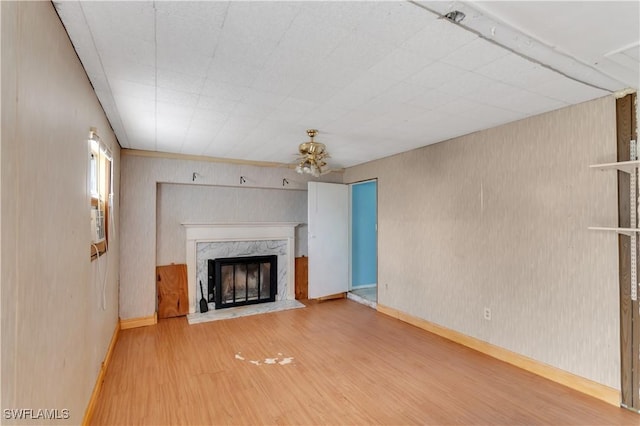 unfurnished living room with ceiling fan, a fireplace, and wood-type flooring