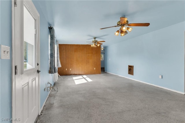 carpeted spare room with ceiling fan and wood walls