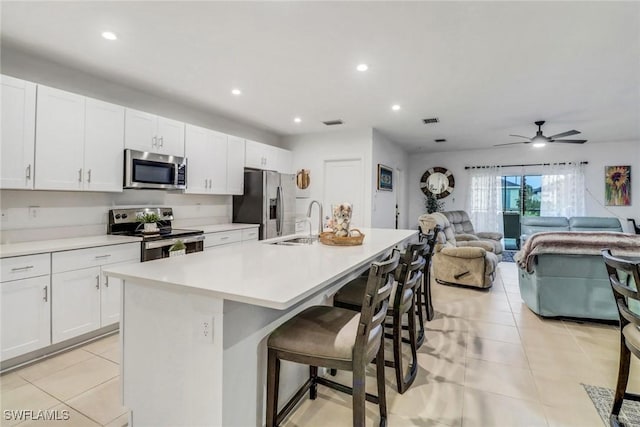 kitchen featuring stainless steel appliances, sink, a center island with sink, white cabinetry, and a breakfast bar area