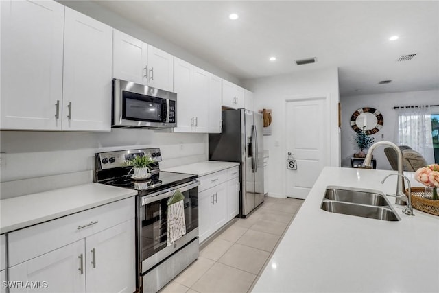 kitchen with white cabinets, stainless steel appliances, light tile patterned flooring, and sink