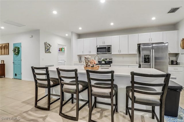 kitchen featuring white cabinets, appliances with stainless steel finishes, and a large island with sink