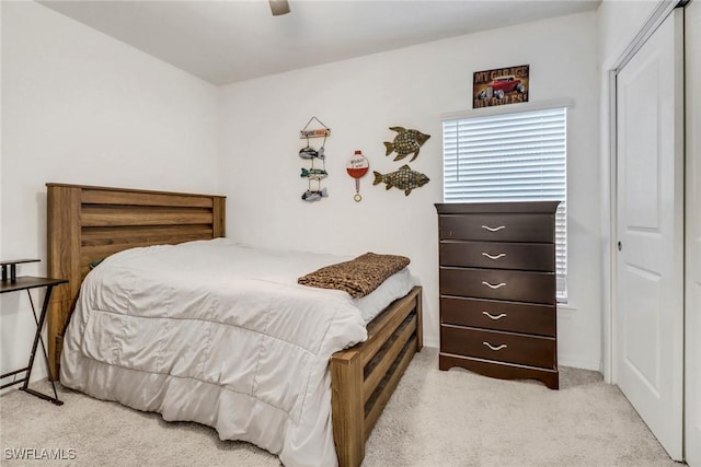 bedroom with ceiling fan, a closet, and light carpet