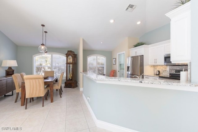 kitchen featuring stainless steel appliances, pendant lighting, light tile patterned floors, white cabinets, and lofted ceiling